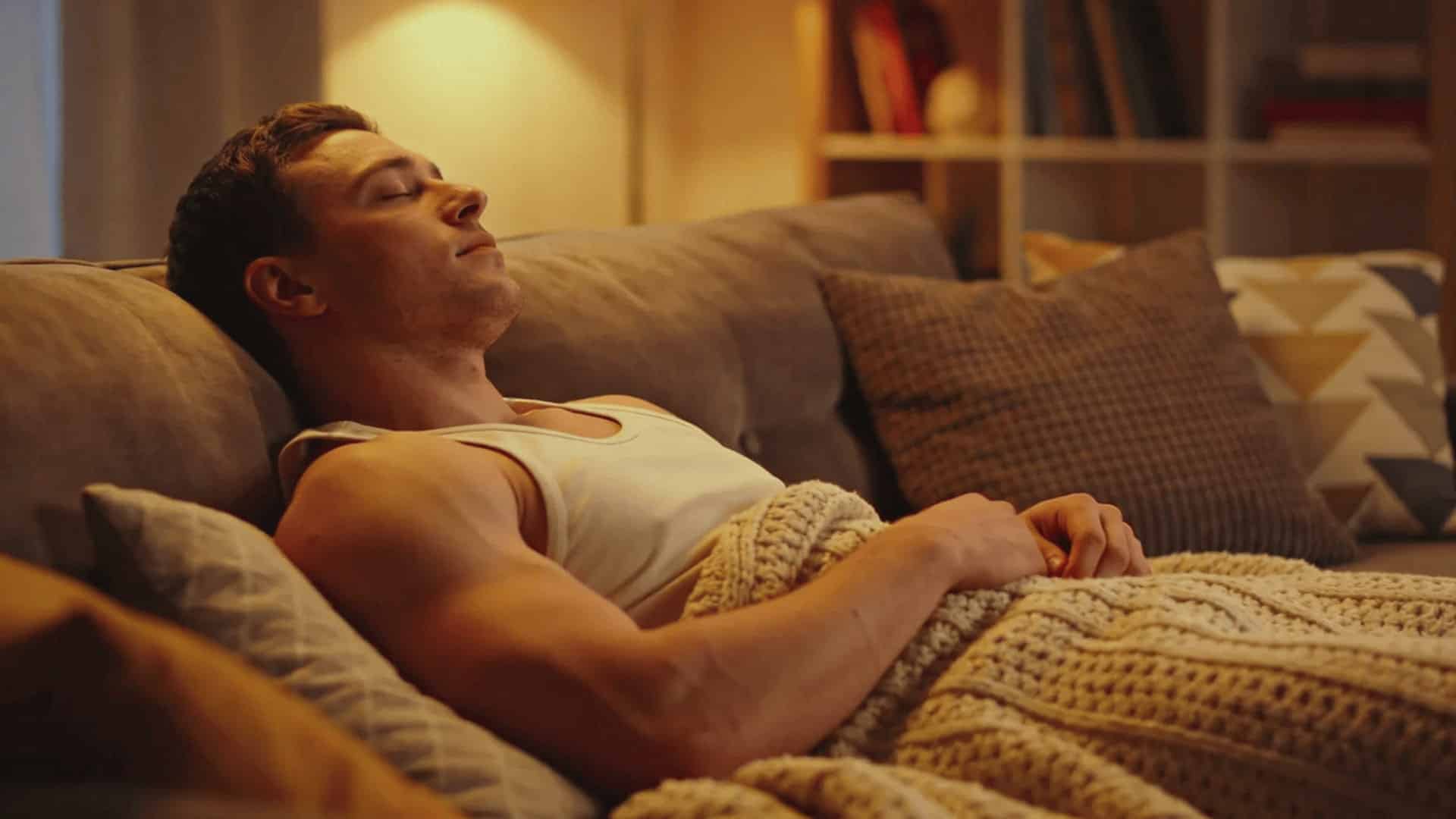 person reclining on couch in cozy warmly lit living room with calm relaxed expression and soft evening lighting