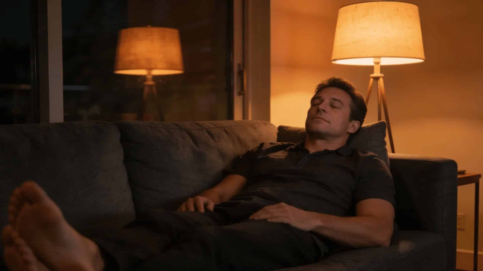person relaxing on a couch at night, with a peaceful expression and soft lighting in the background