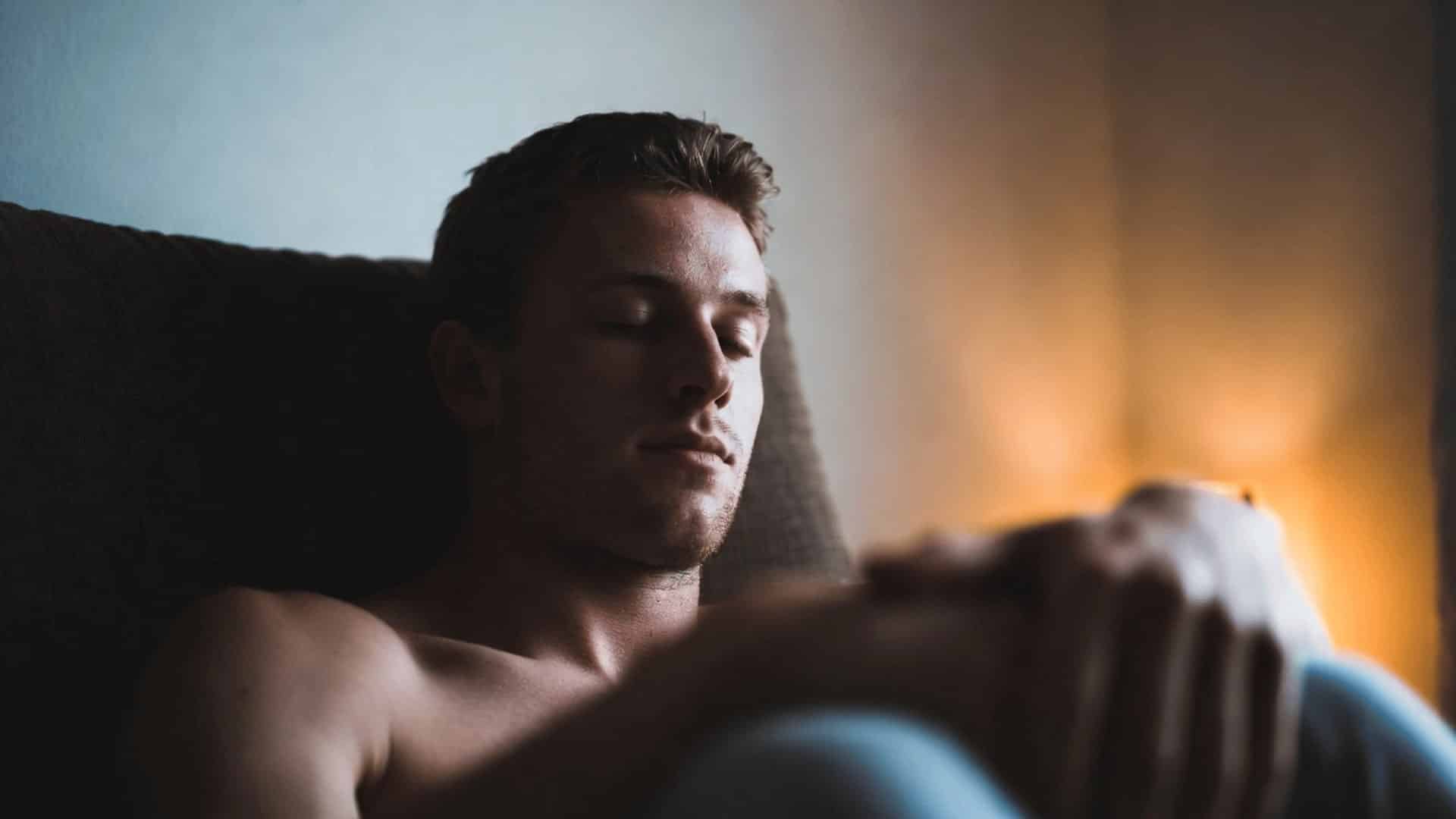 person sitting relaxed in chair with loose shoulders and calm expression showing physical ease and tension release
