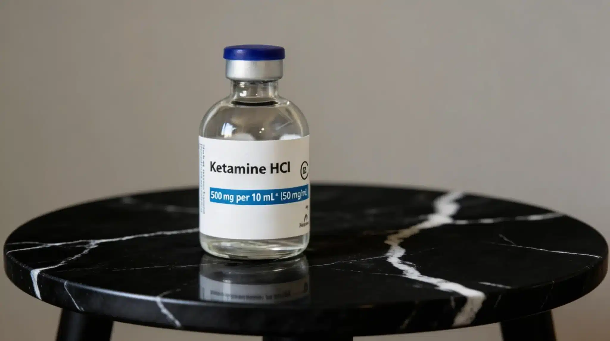 a clear bottle of ketamine hci 500 mg per 10 ml on a black marble table with white veins