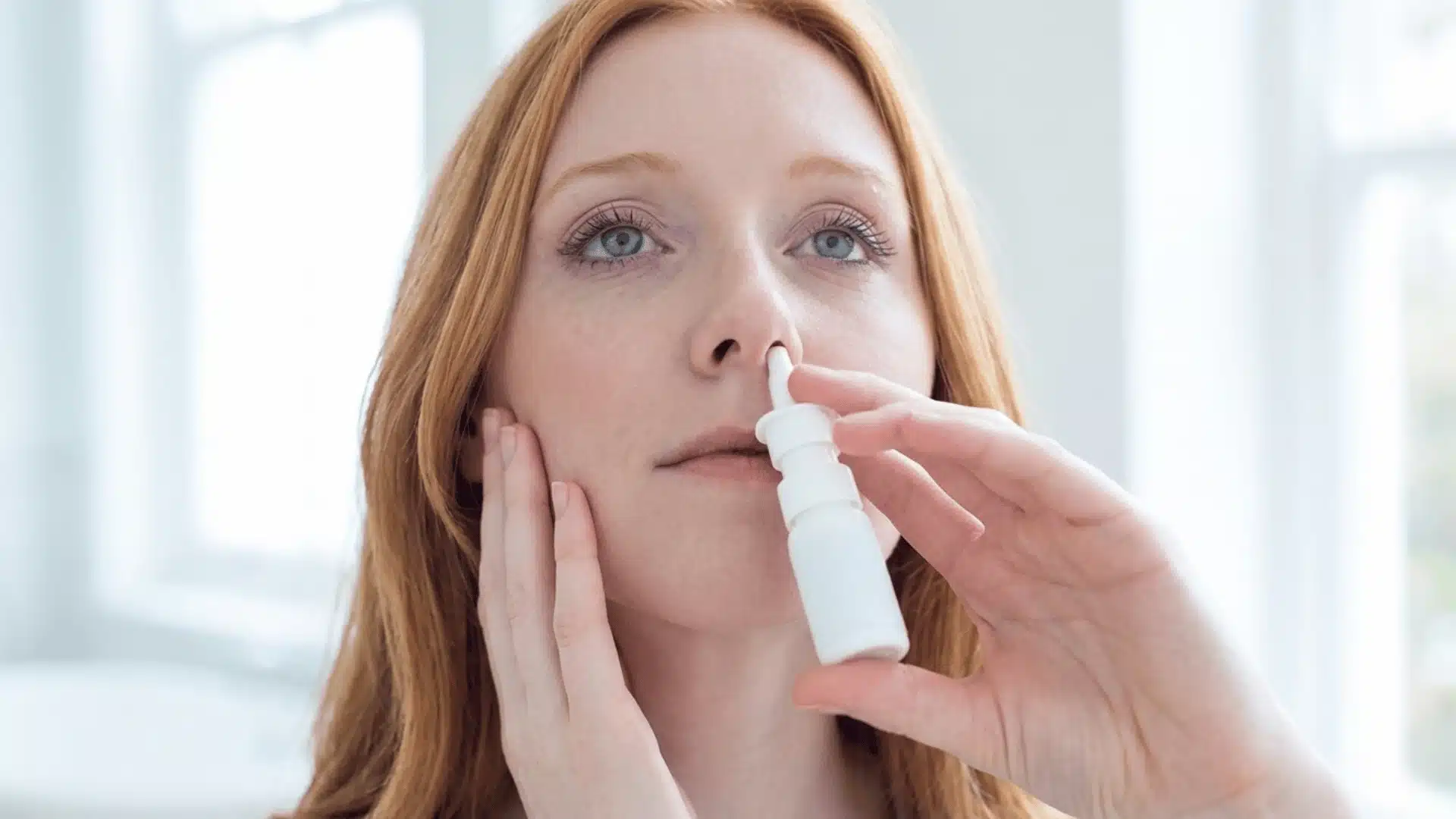 close-up photograph of a young caucasian woman administering nasal medication