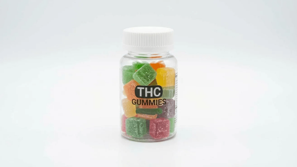 colorful thc gummies kept in a clear jar on a white surface for natural pain relief
