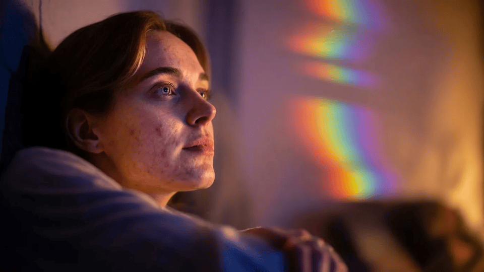 person sitting in dim room observing soft colorful lights with blurred surroundings