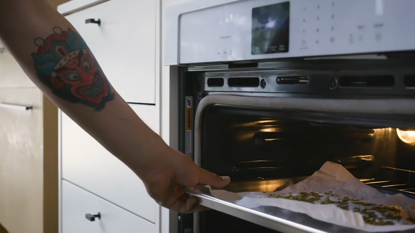decarb weed in oven scene with a tray of cannabis on parchment paper being placed into a warm oven