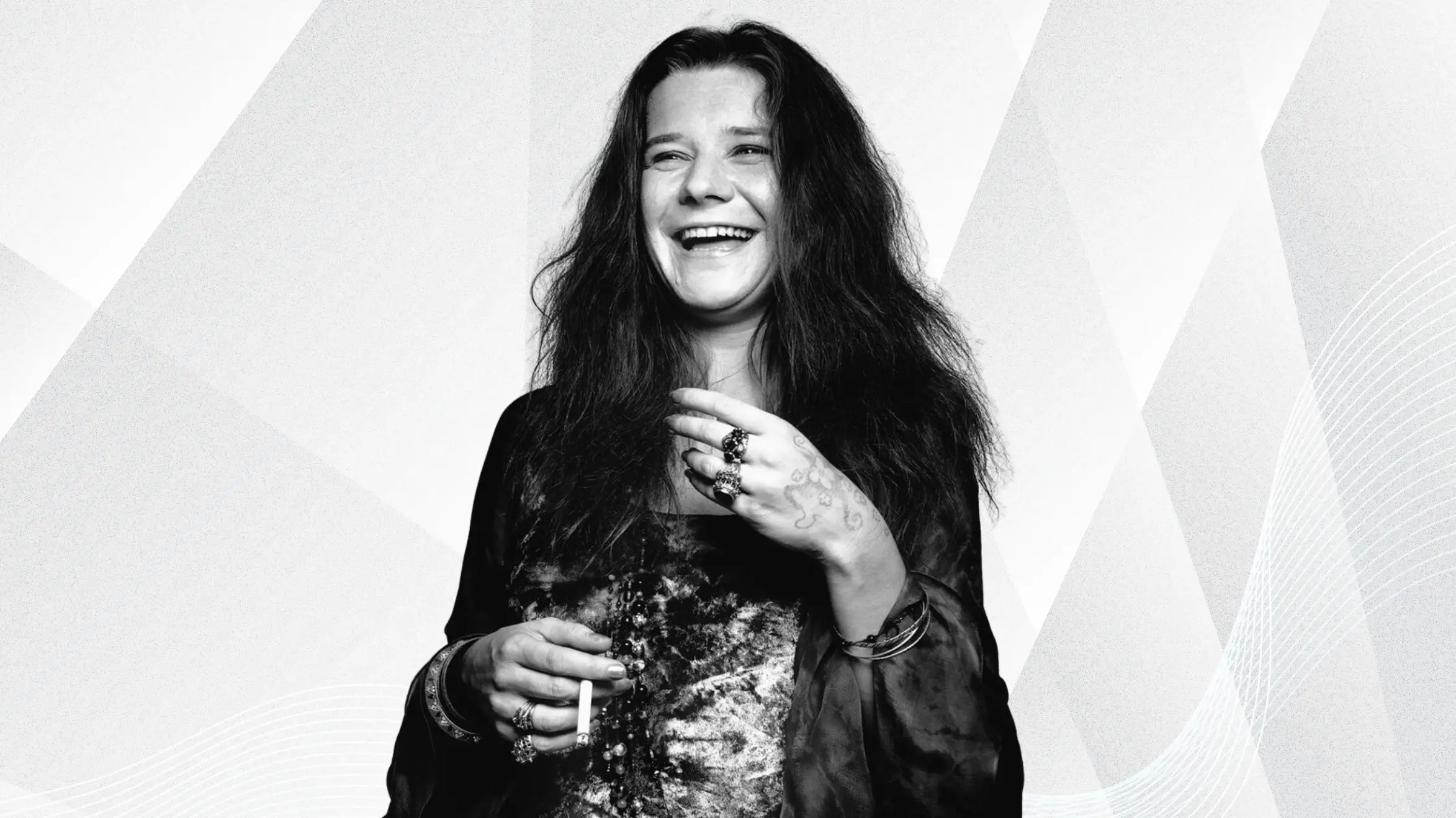 black and white portrait of smiling woman with long hair, holding cigarette, wearing rings and bracelets