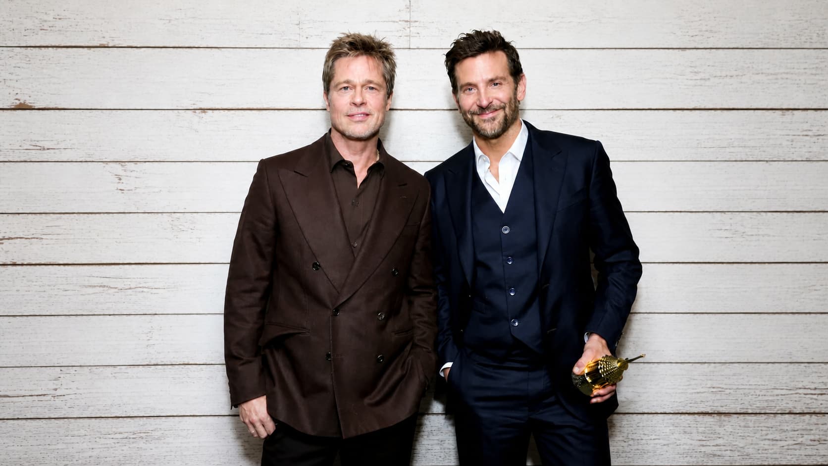 brad pitt and bradley cooper smiling together while posing at a film festival awards event