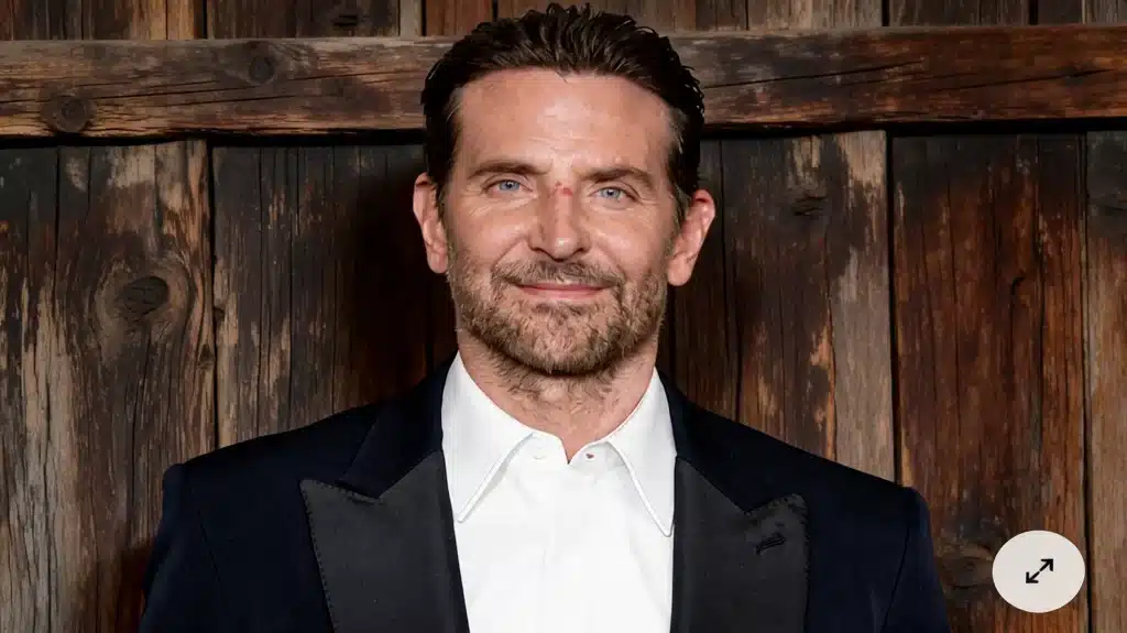 bradley cooper smiling in black tuxedo suit portrait against rustic wooden background