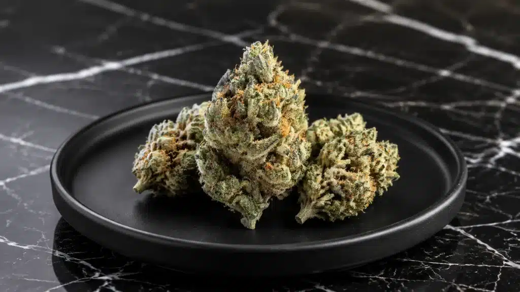 cannabis buds arranged on a matte black plate, placed on a sleek marble countertop with contrasting white veins