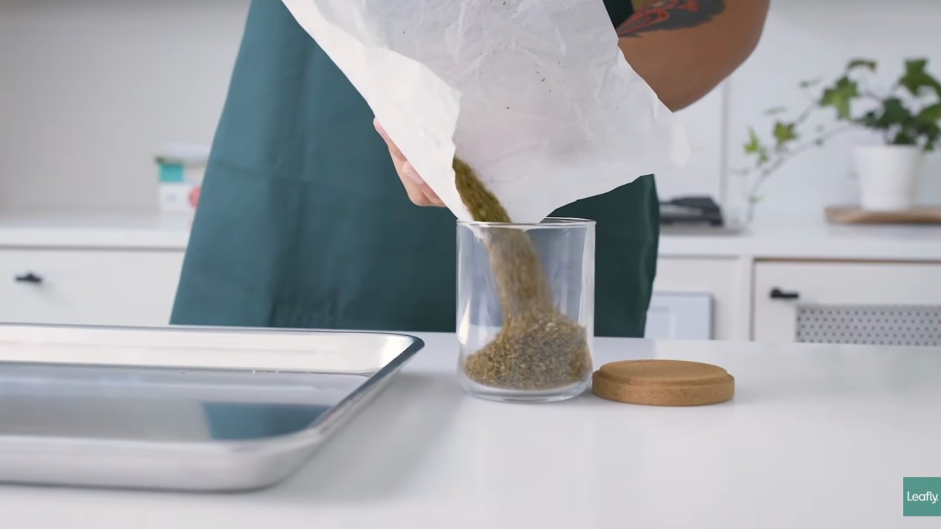 decarb weed in oven result with baked cannabis poured from parchment paper into a clear storage jar