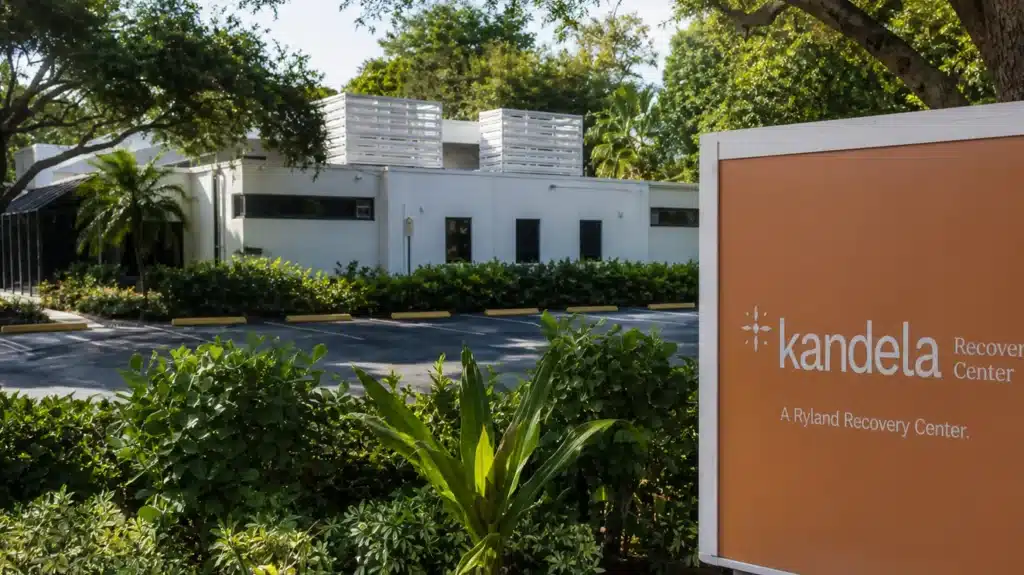 exterior of kandela recovery center building with signage, surrounded by trees, and parking area in bright light