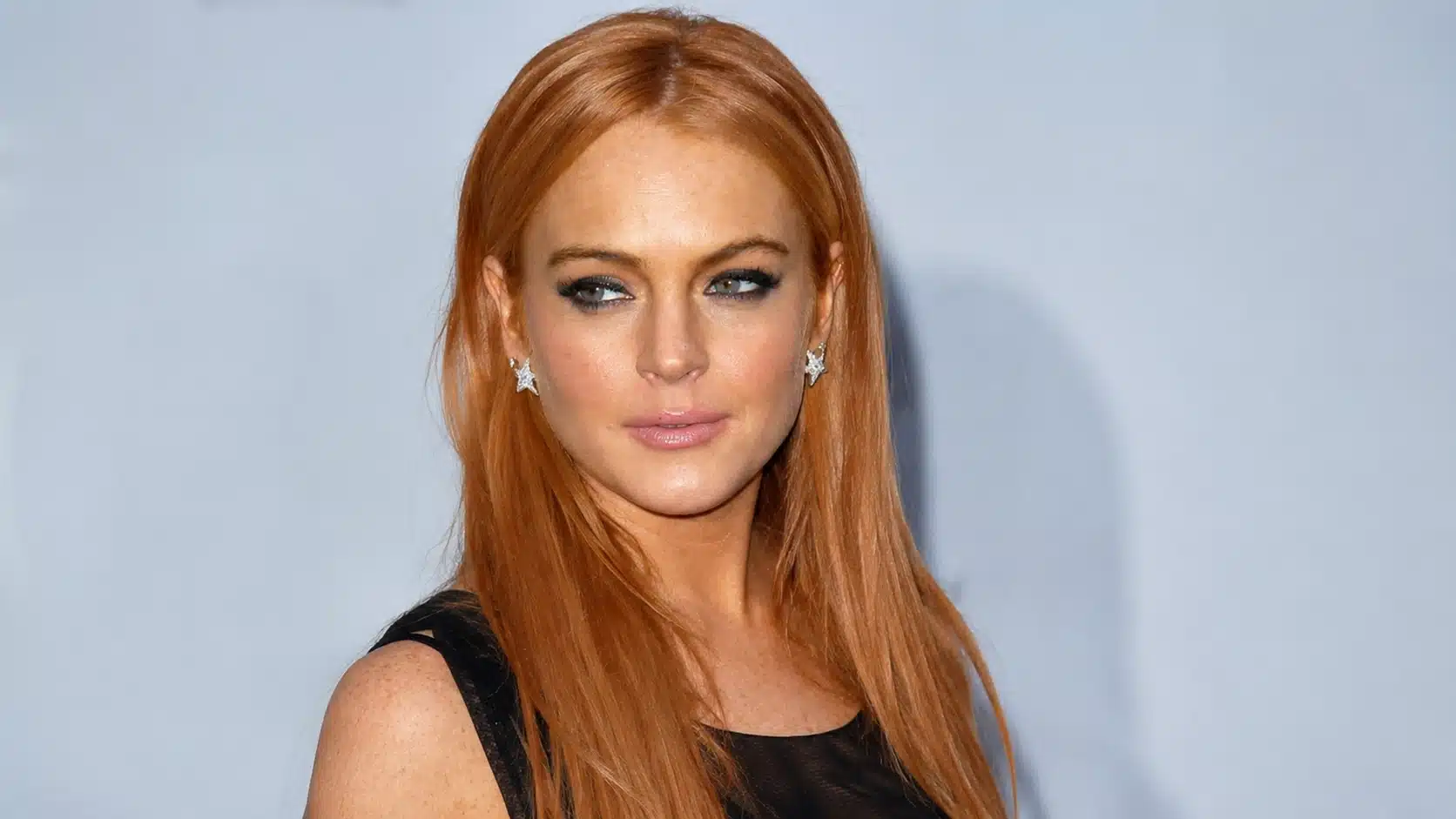 image for lindsay lohan during drug phase showing strawberry blonde woman in black dress against pale backdrop