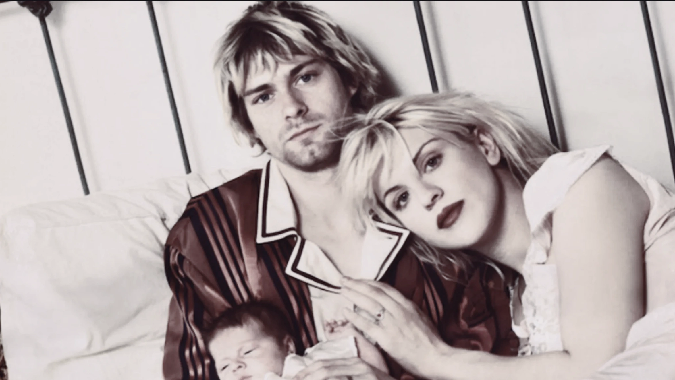 kurt cobain and courtney love lying together in bed with their newborn daughter, frances bean cobain, between them