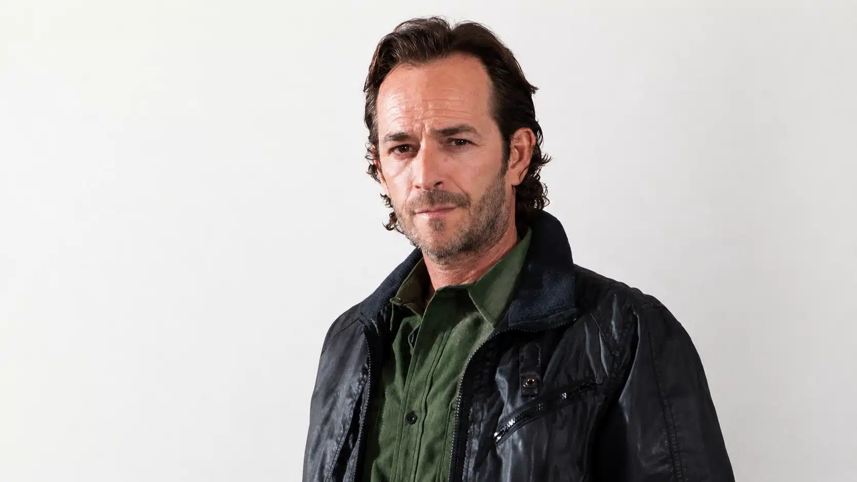 luke perry drugs topic image showing a serious man in black leather jacket and green shirt against a white wall