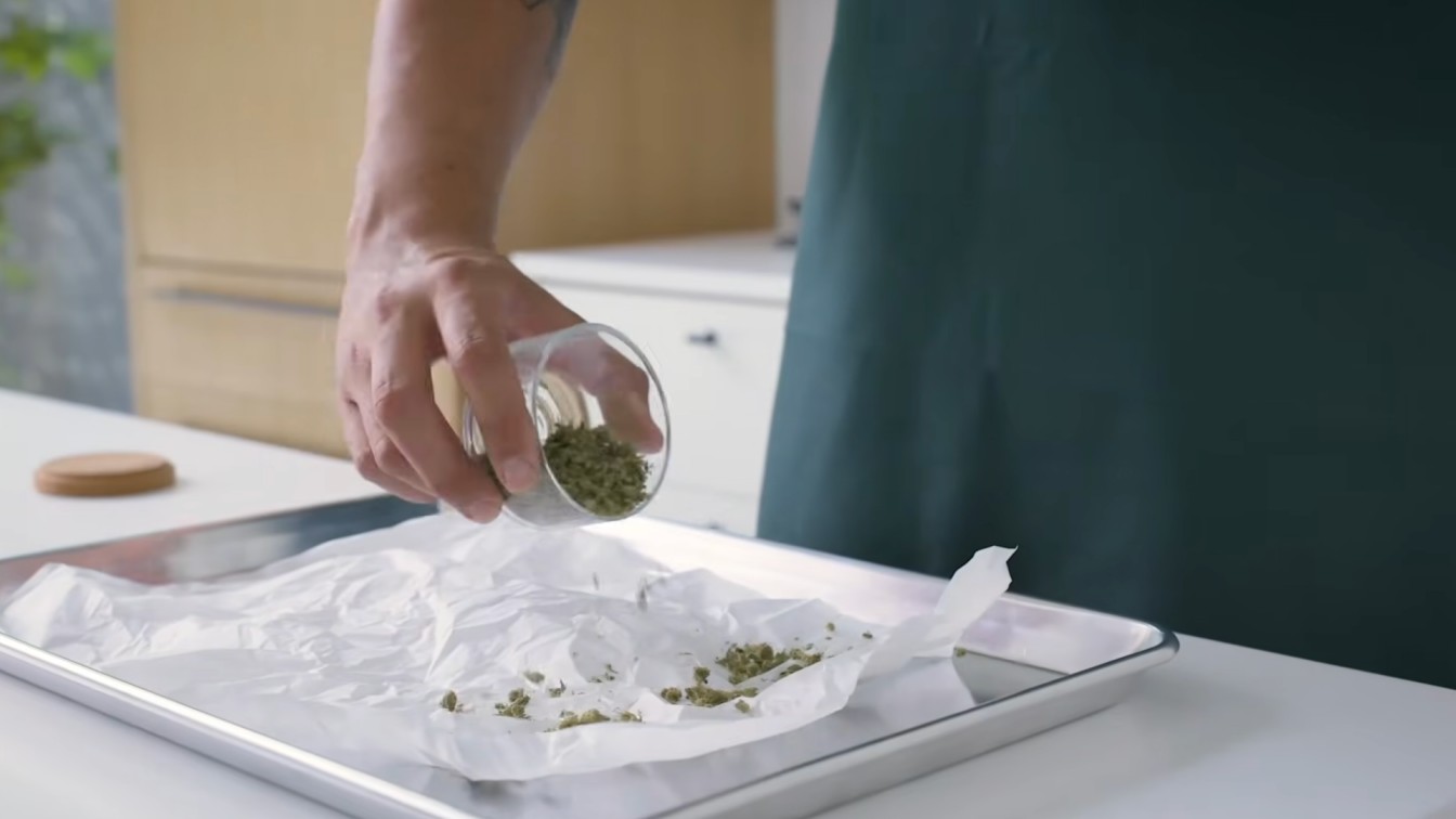 decarb weed in oven setup with ground cannabis poured onto parchment paper on a metal baking tray
