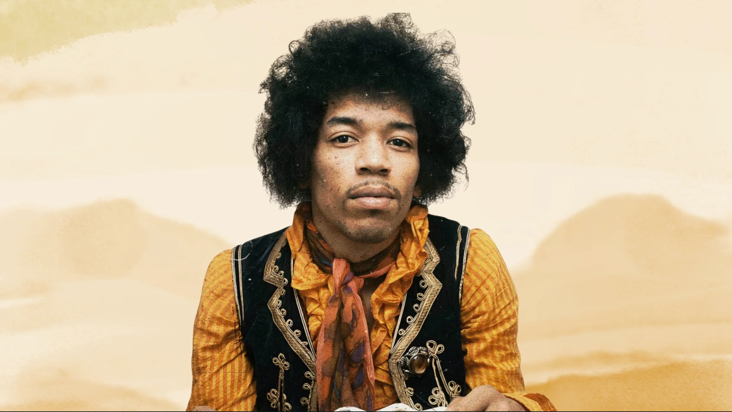 portrait of man with afro hairstyle wearing patterned shirt and vest, looking at camera against soft beige background