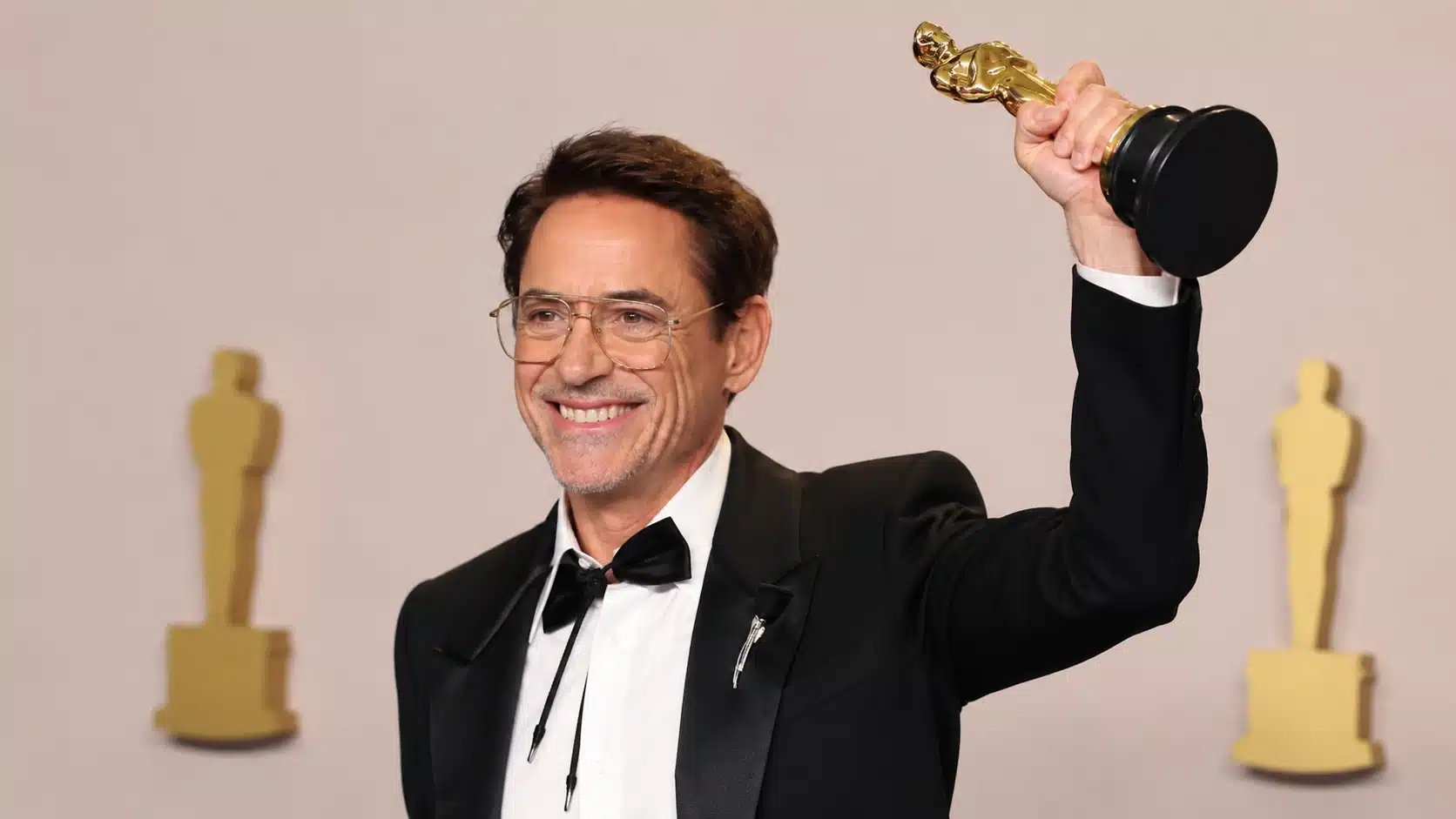 robert downey jr. holding an award in a tuxedo, symbolizing comeback after robert downey jr drugs and career struggles