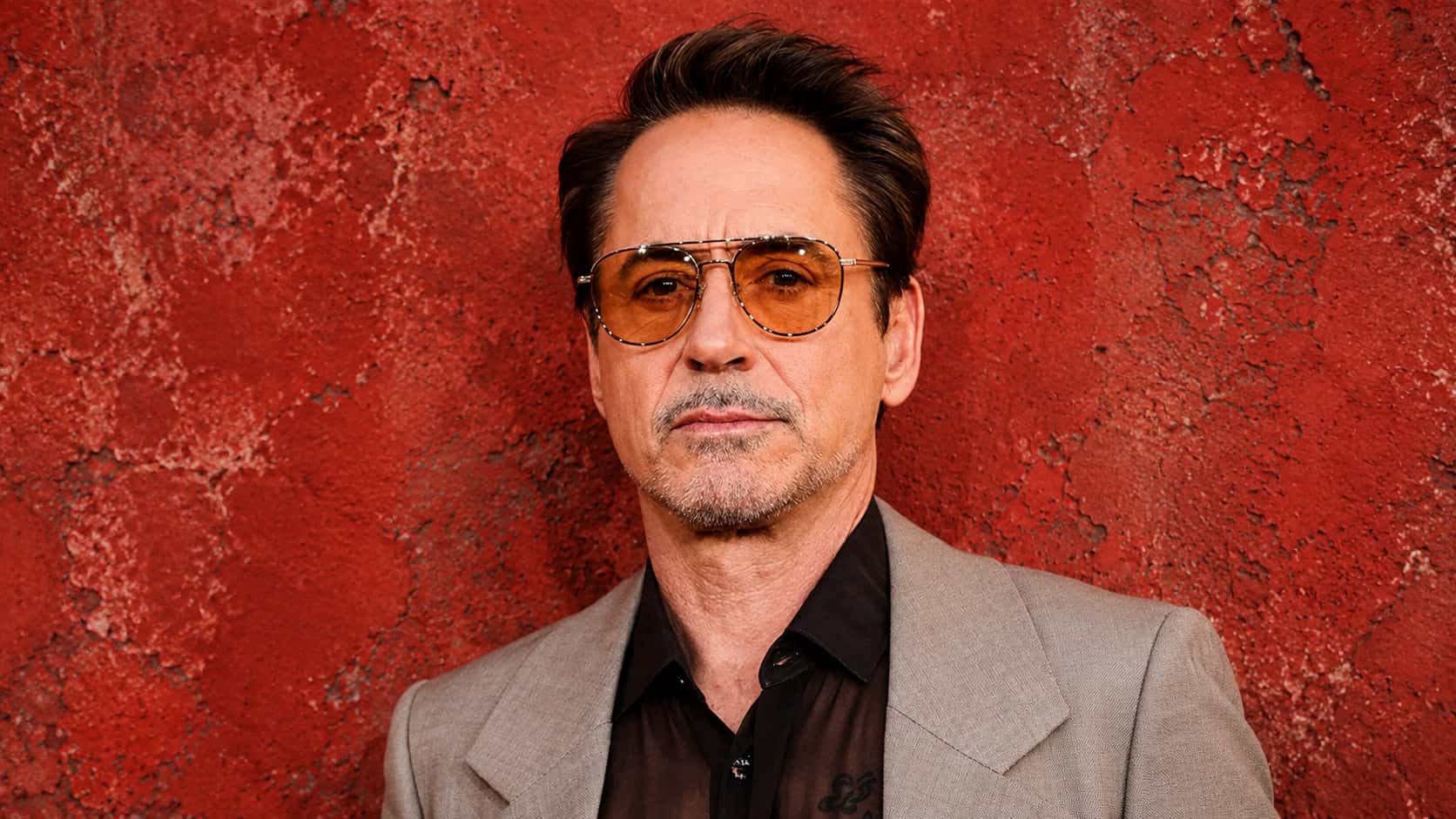 robert downey jr. standing against a red rustic wall