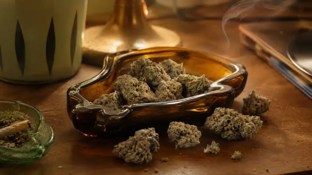 cannabis buds fill a retro amber ashtray on a wooden table with smoke, vintage decor, and warm 1960s atmosphere lighting