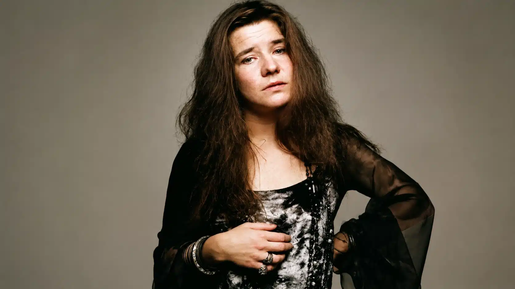 portrait of janis joplin in black and white dress, standing with hand on chest, referencing janis joplin cause of death