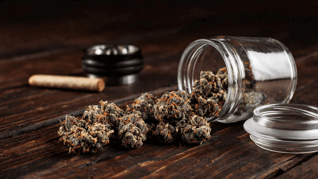 transparent open jar full of forbidden fruit cannabis buds on a wood table